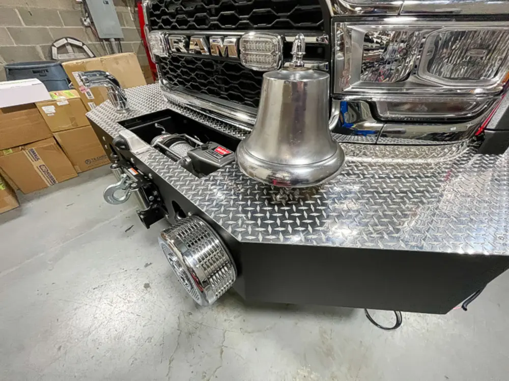 Exterior view of small fire truck showing cab, body compartments, and wheel/tire area.